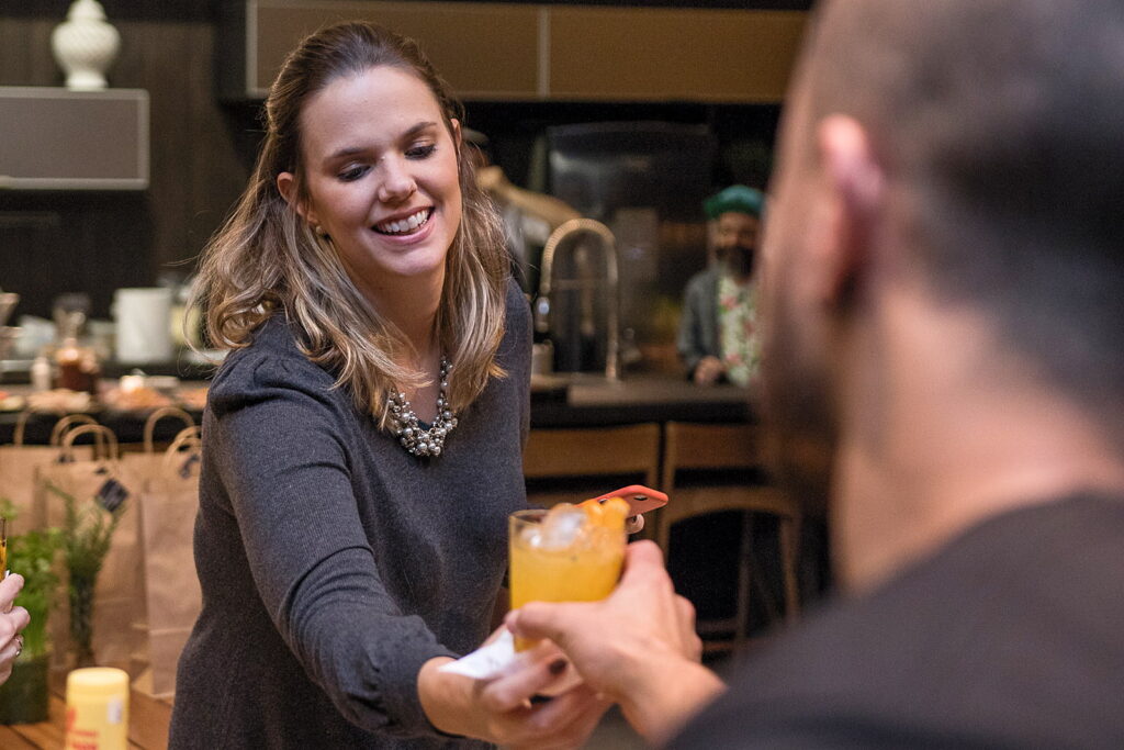 Recepcionista entrega o drink de boas-vindas a um convidado na chegada do evento corporativo