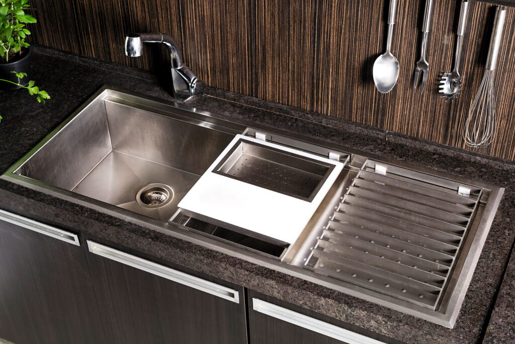 Cuba de inox embutida na bancada de pedra do Amazônia Gourmet, com os utensílios na parede ripada