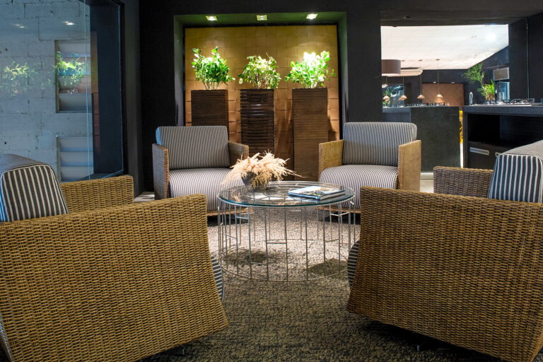 Lounge de poltronas do Amazônia Gourmet, com jardim vertical ao fundo e a cozinha logo atrás