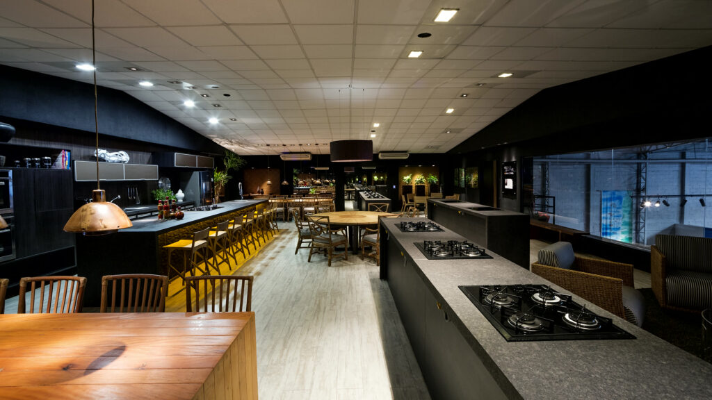 Salão do Amazônia Gourmet com bancada de cocção, mesa comunitária e banquetas