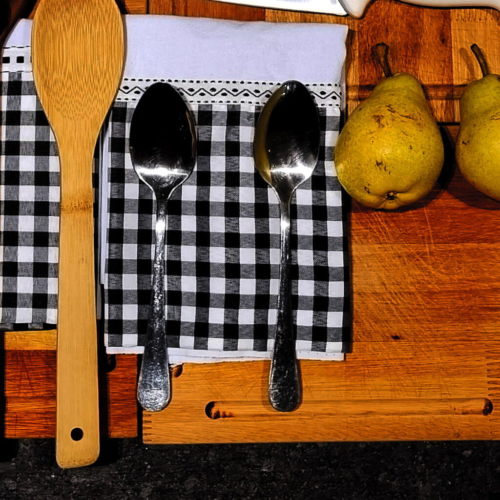 Tábua de madeira do Amazônia Gourmet com utensílios, pano xadrez e frutas preparados para a aula