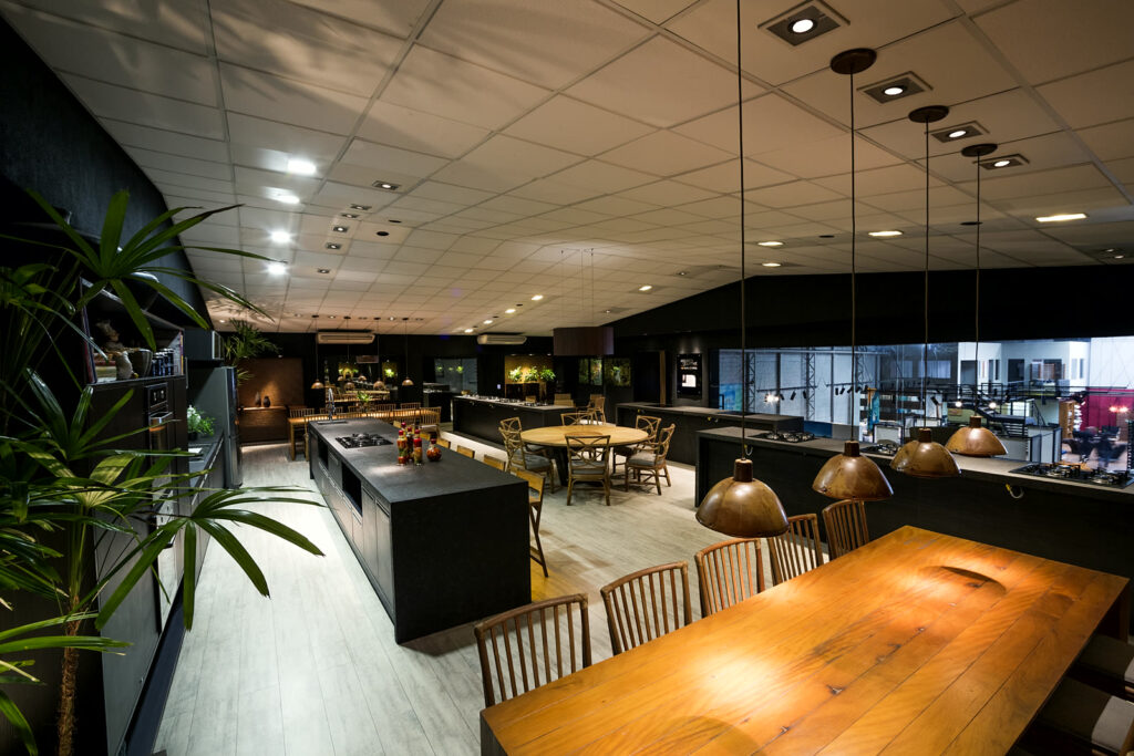Salão do Amazônia Gourmet visto do lounge, com mesa longa e bancadas ao fundo